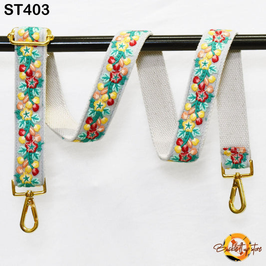 A colorful floral-patterned strap with gold hardware, hanging on a black bar.