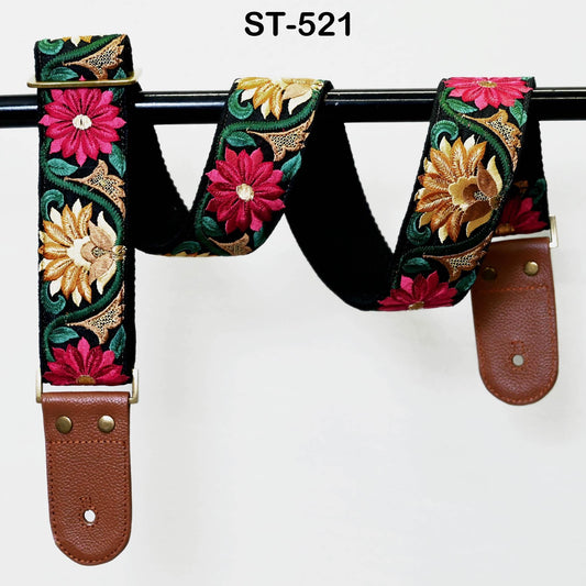 A colorful guitar strap with floral patterns, hanging on a black metal bar.