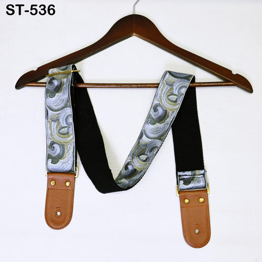 A brown wooden hanger with a patterned strap attached to it, displayed against a white background.