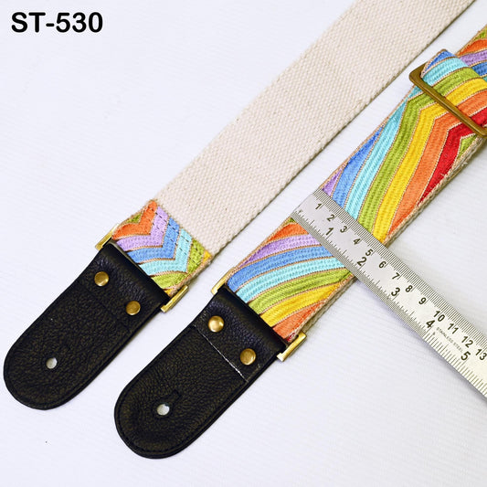 a colorful guitar strap with a ruler placed next to it, indicating the strap's length.