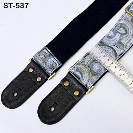 A black and silver patterned guitar strap with a ruler placed on top of it, indicating the size of the strap.