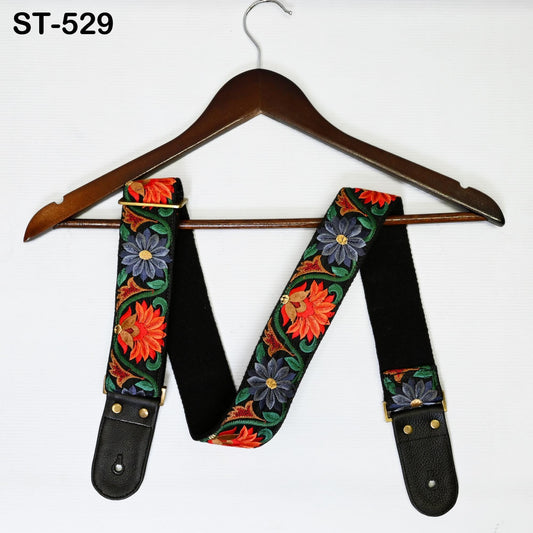 A wooden hanger with a floral patterned guitar strap hanging on it.