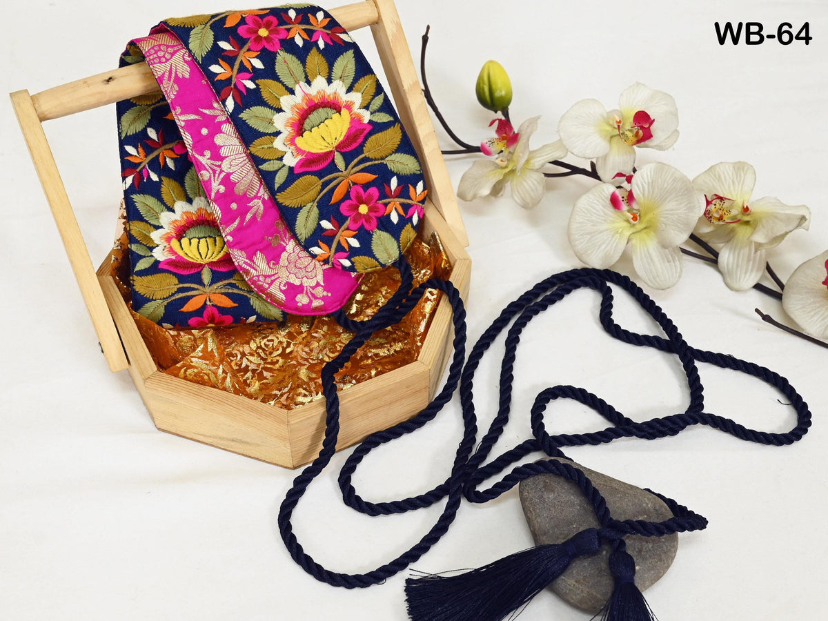 a wooden basket with a colorful floral pattern, a pink and blue scarf, a blue string, and a small white orchid flower.