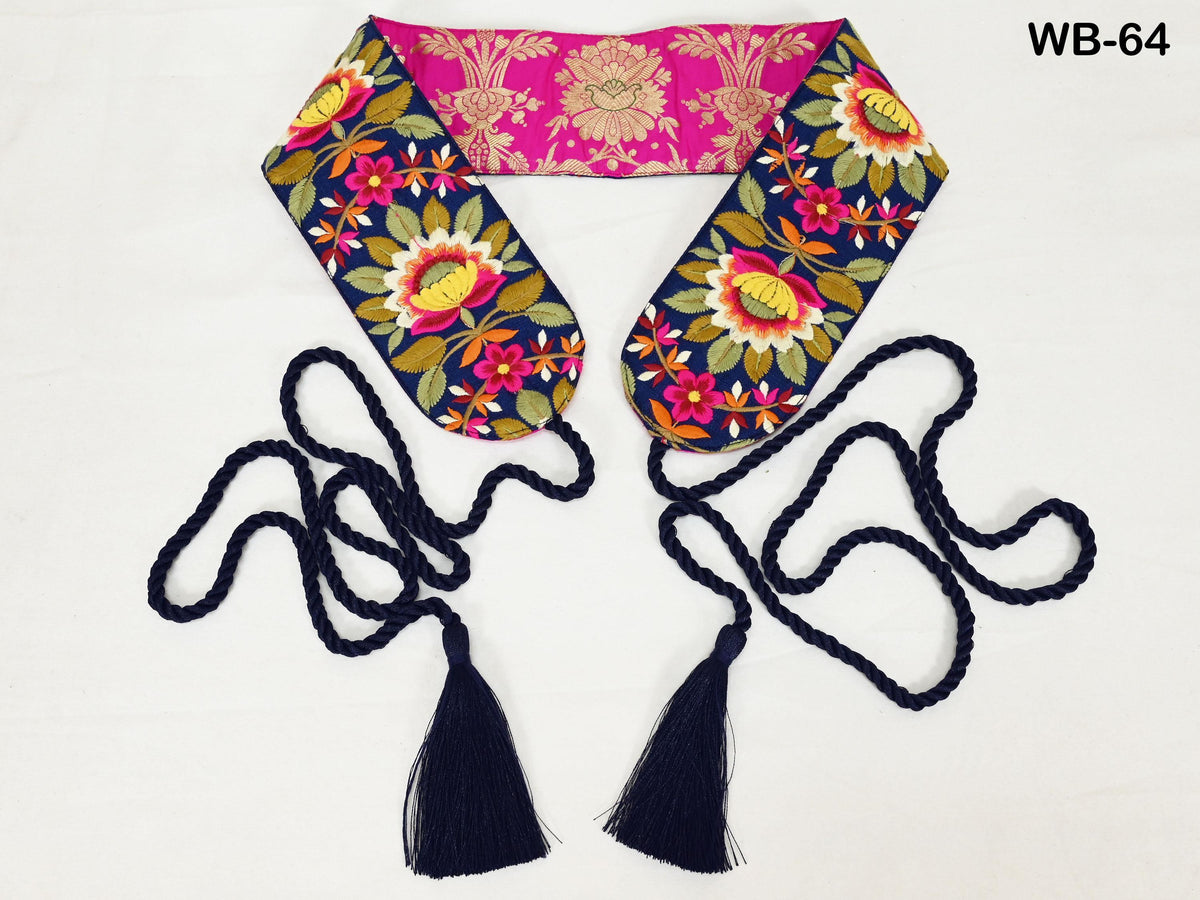 a colorful, floral-patterned scarf with a pink and gold design, and two black tassels hanging from the ends of the scarf.