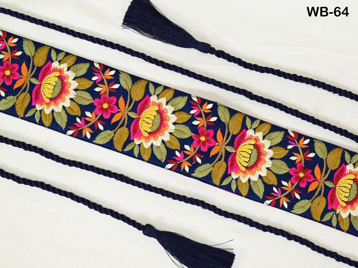 a decorative fabric with a floral pattern in shades of blue, green, and pink. The fabric is adorned with a tassel and is displayed on a white background.