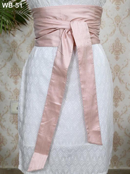 A mannequin wearing a white dress with a pink sash tied around the waist.