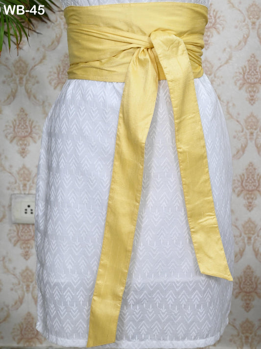 A white dress with a yellow sash tied around the waist.