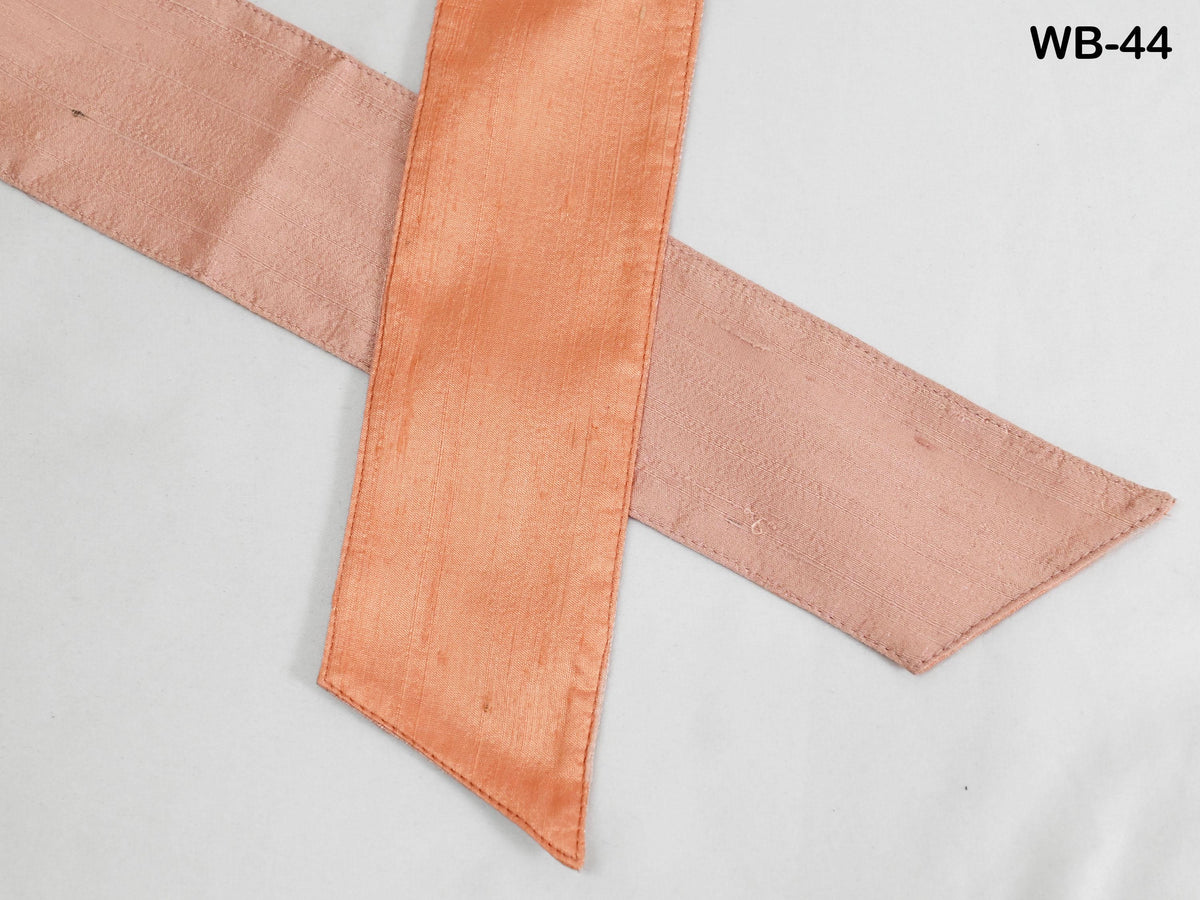 a close-up view of a pink and orange ribbon or fabric, with the pink ribbon appearing slightly wrinkled and the orange ribbon appearing smoother.