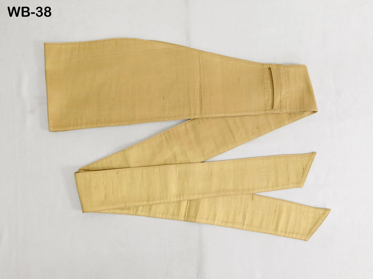 a gold-colored fabric, possibly a belt or scarf, lying on a white surface.