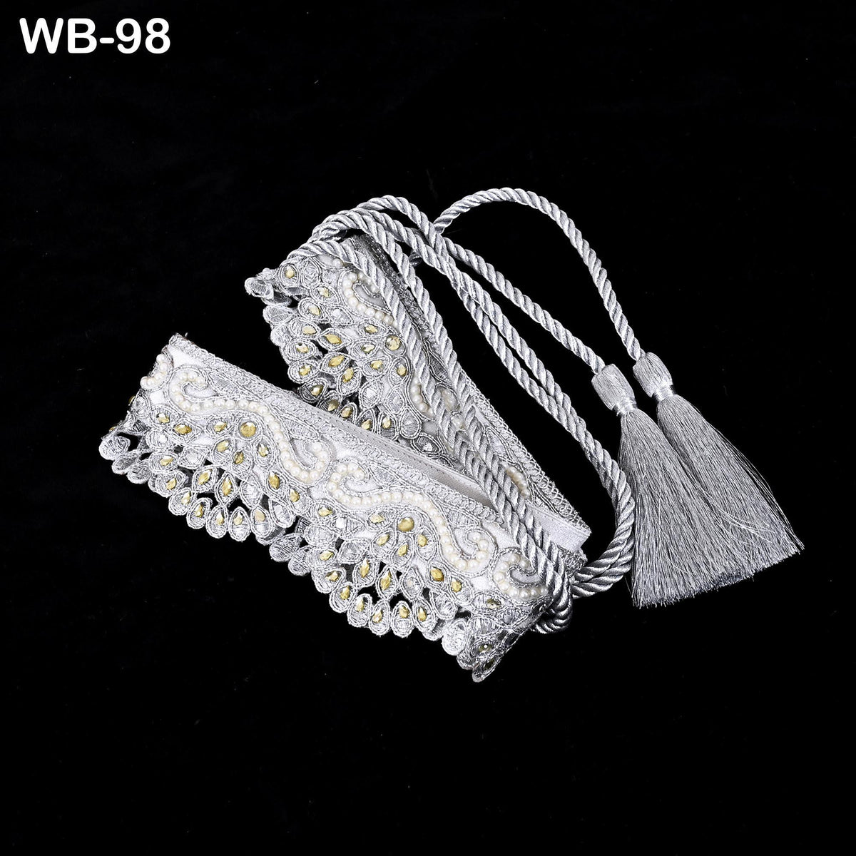 A decorative white lace bracelet with a tassel attached, displayed against a black background.