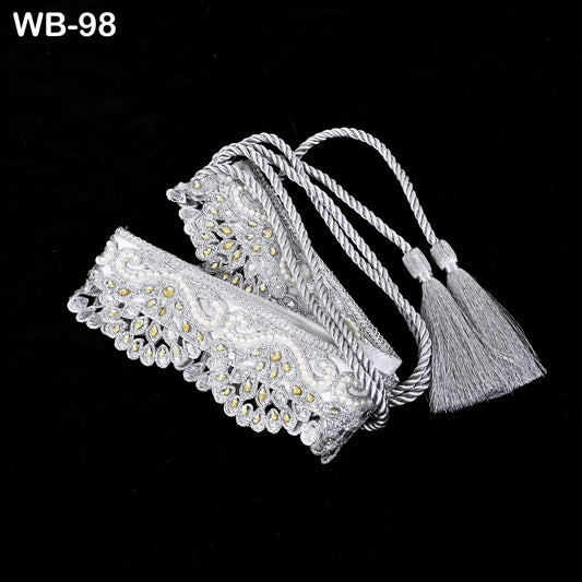 A decorative white lace bracelet with a tassel attached, displayed against a black background.