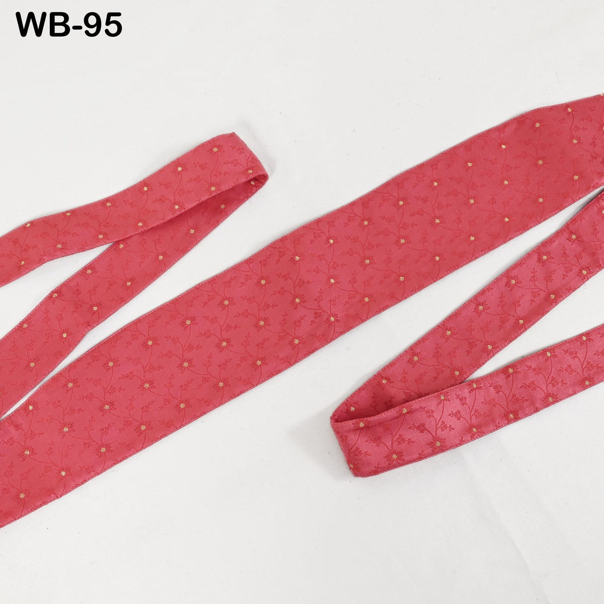 a red tie with a floral pattern, lying on a white surface.