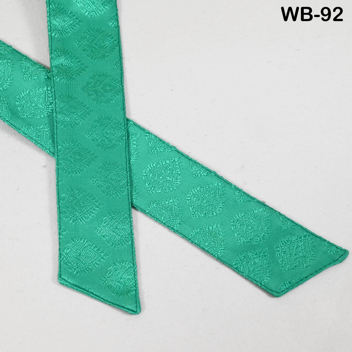 a pair of green fabric ribbons with a repeating pattern of small circles on them.