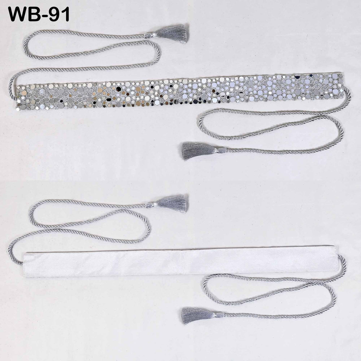 two silver-colored belts with tassels, one with a tassel on the left and the other with a tassel on the right, both lying on a white surface.