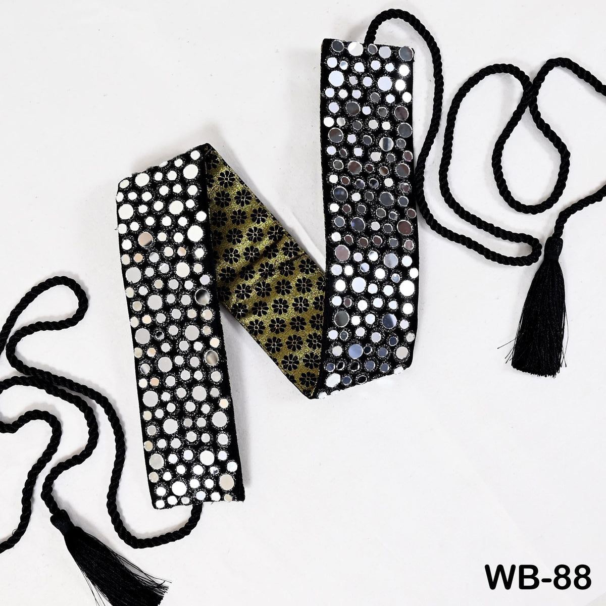 A decorative item with a black and white polka dot pattern and a gold floral pattern, featuring a tassel on the right side.