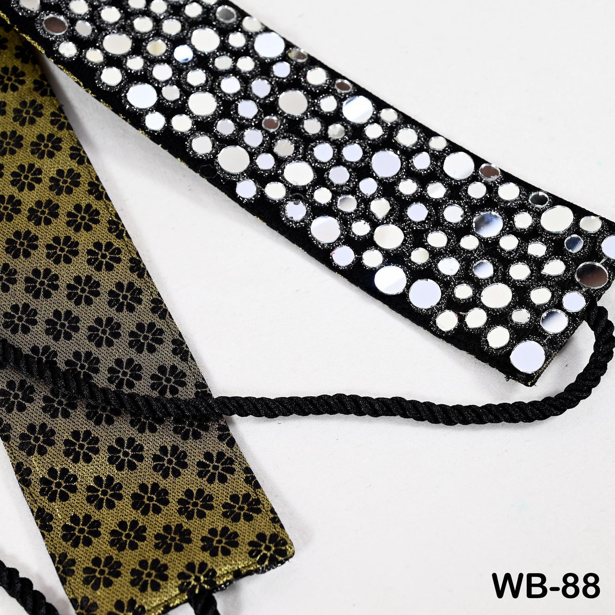 a close-up view of a decorative fabric with a floral pattern and a black and white polka dot design. The fabric appears to be a tie or headband, with a black rope or cord attached to it.