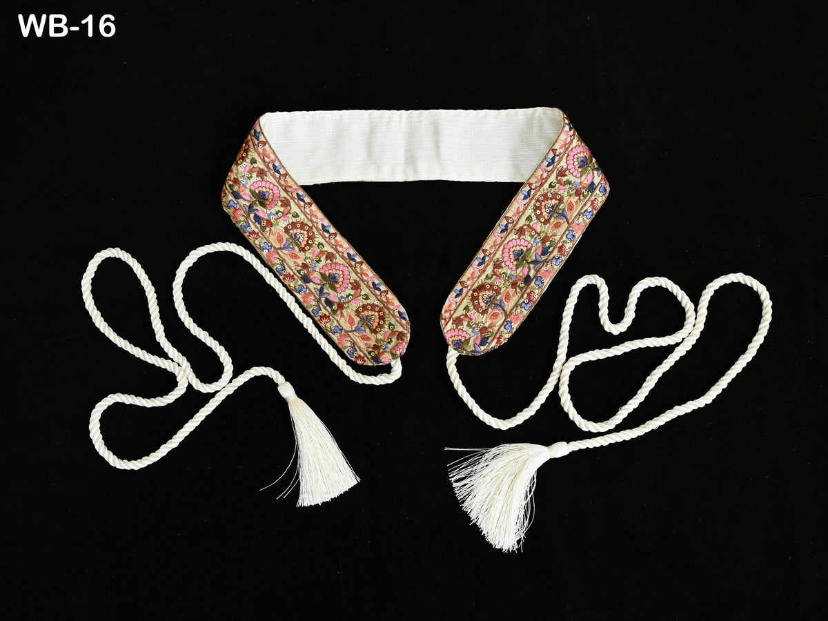 a decorative collar with a floral pattern and two white tassels, one on each side, against a black background.
