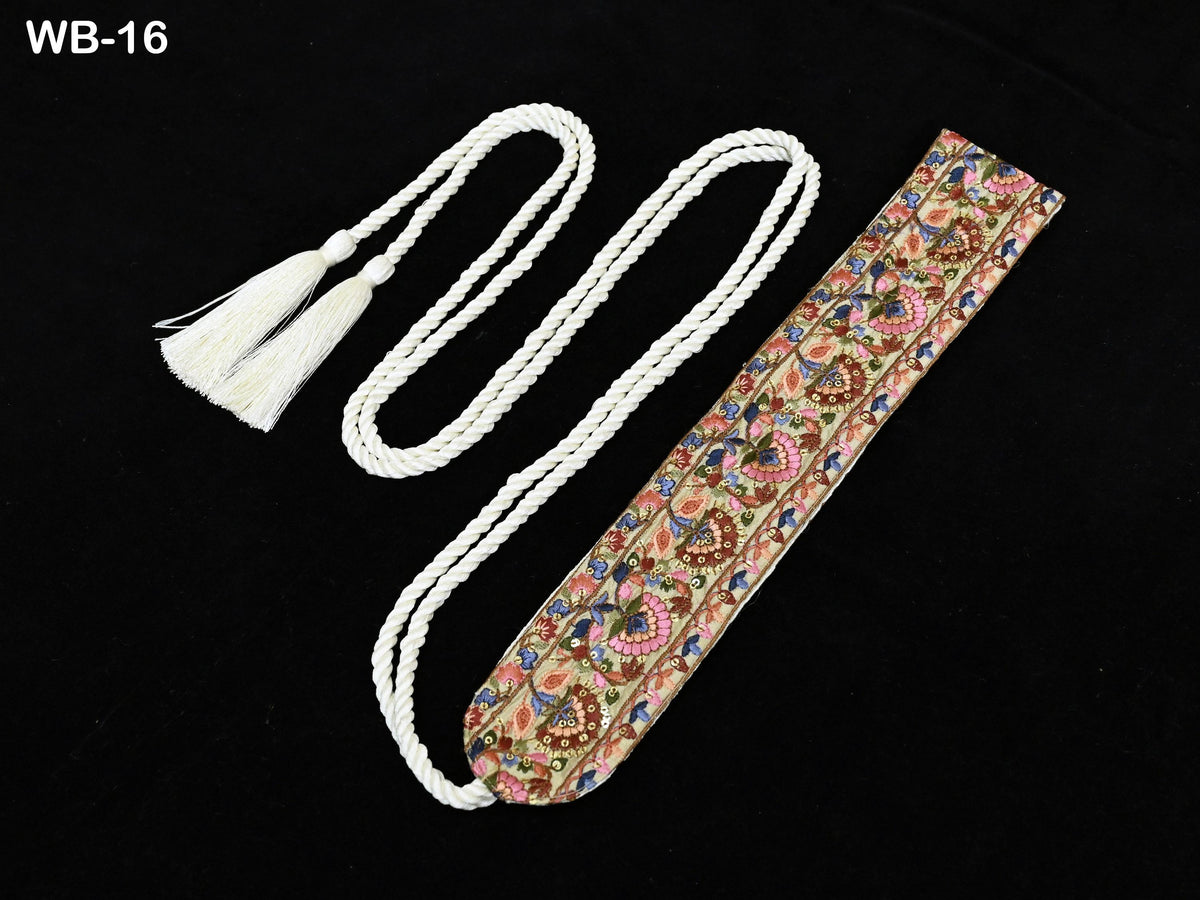 A decorative tassel with a floral pattern and a white rope attached to it, placed on a black background.
