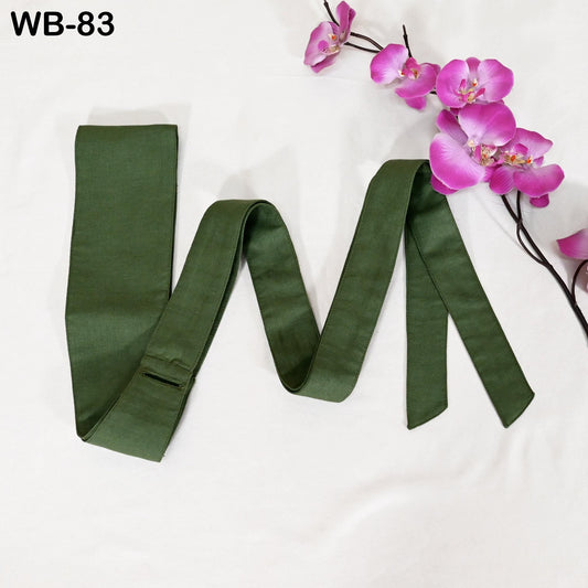 a green tie with a floral arrangement of pink orchids placed next to it on a white background.