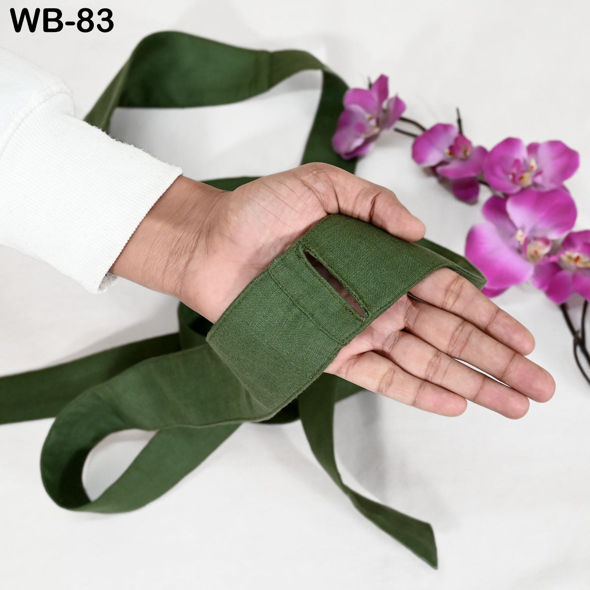 A hand holding a green fabric with a floral pattern, next to a bunch of pink orchids.