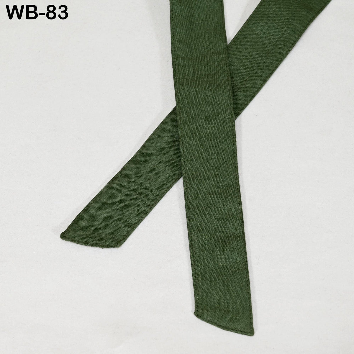a pair of green fabric straps or belts, which appear to be made of a natural material and are lying on a white surface.