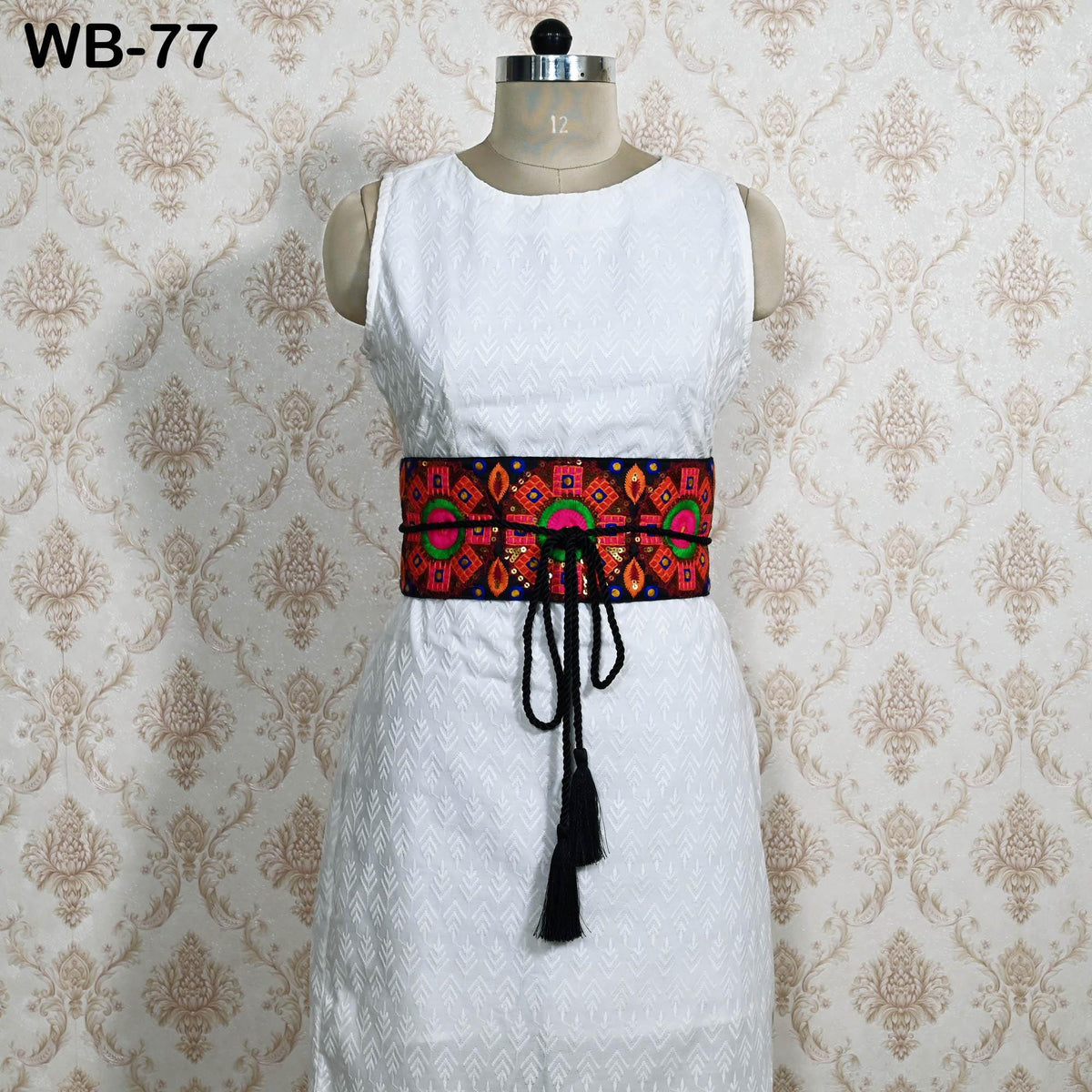A mannequin wearing a white dress with a colorful, patterned belt around the waist.