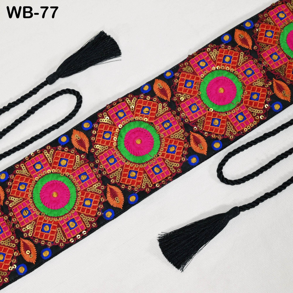 a decorative fabric with a vibrant, colorful floral pattern. The fabric has a black tassel attached to the ends, adding a contrasting element to the overall design.