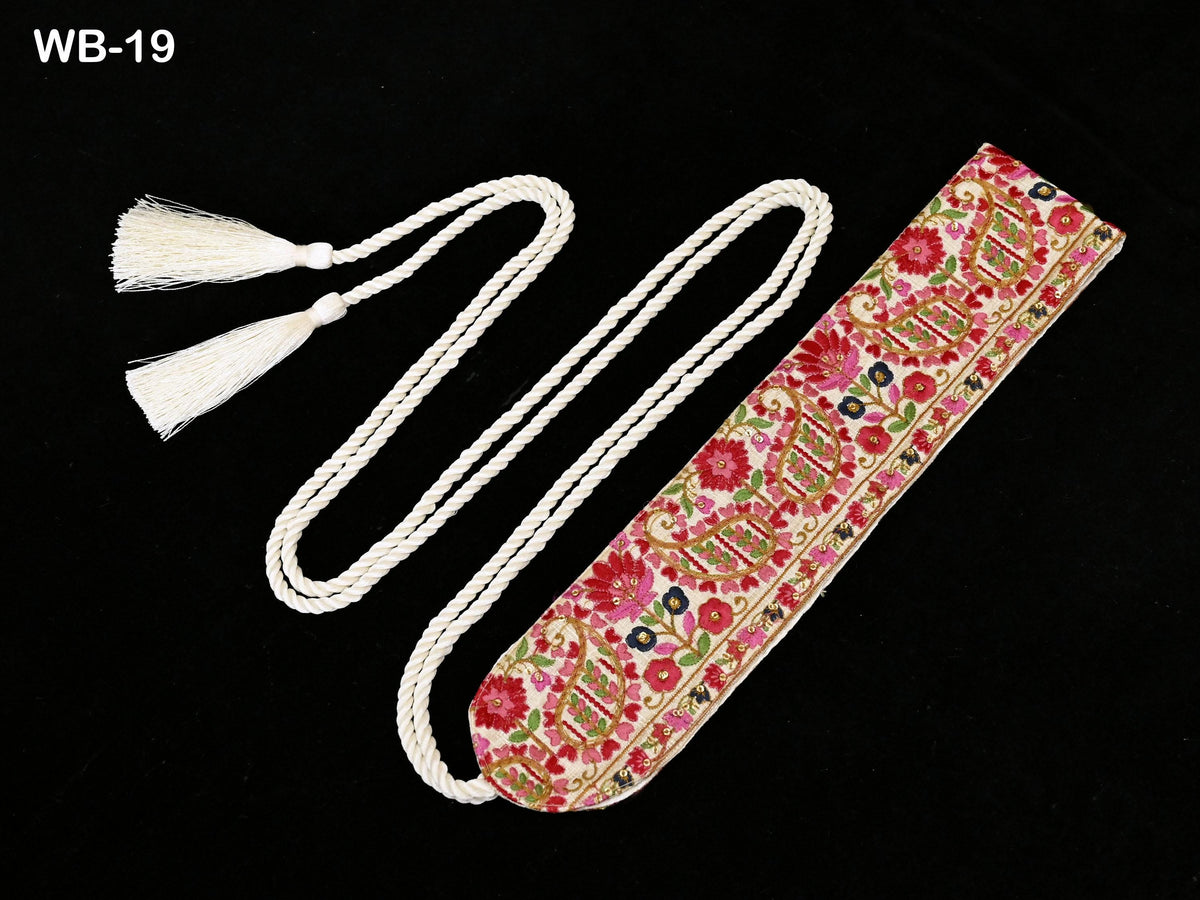 A decorative item with a floral pattern and white tassels, placed on a black background.