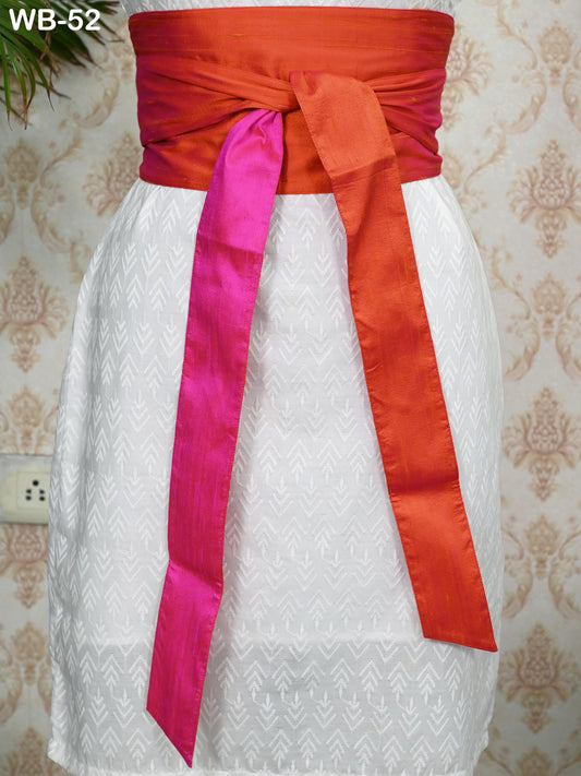 a white dress with a red and pink sash tied around the waist. The dress appears to be a part of a collection or a fashion display.