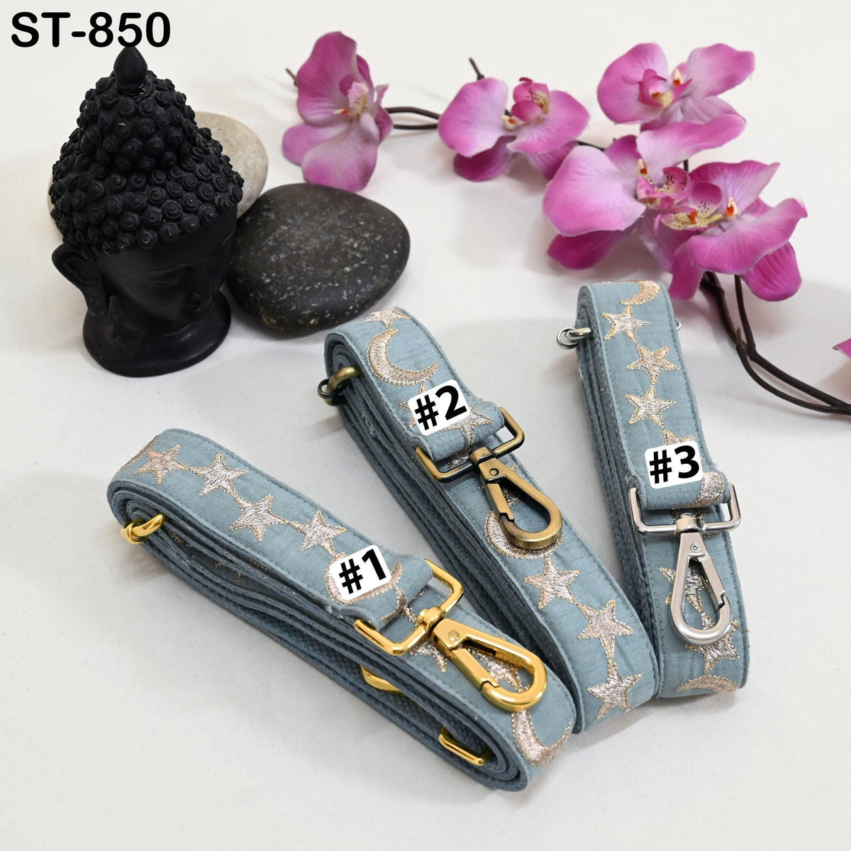 three star-patterned straps with numbers 1, 2, and 3 attached to them, along with a black Buddha statue and pink orchids.