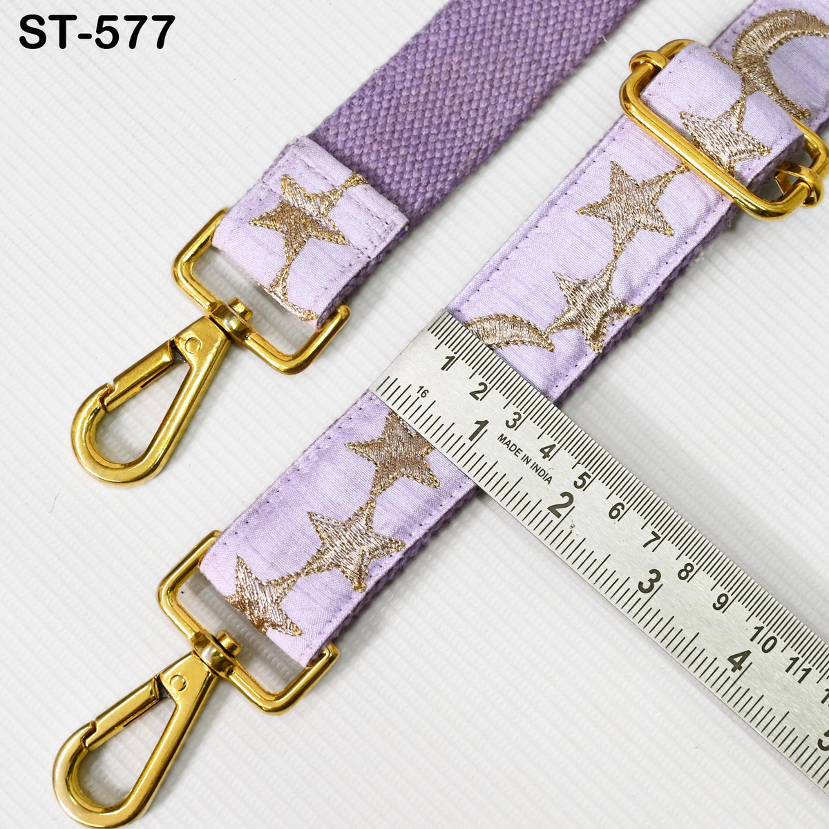 a purple strap with gold star patterns, and a ruler is placed next to it, indicating the strap's length.