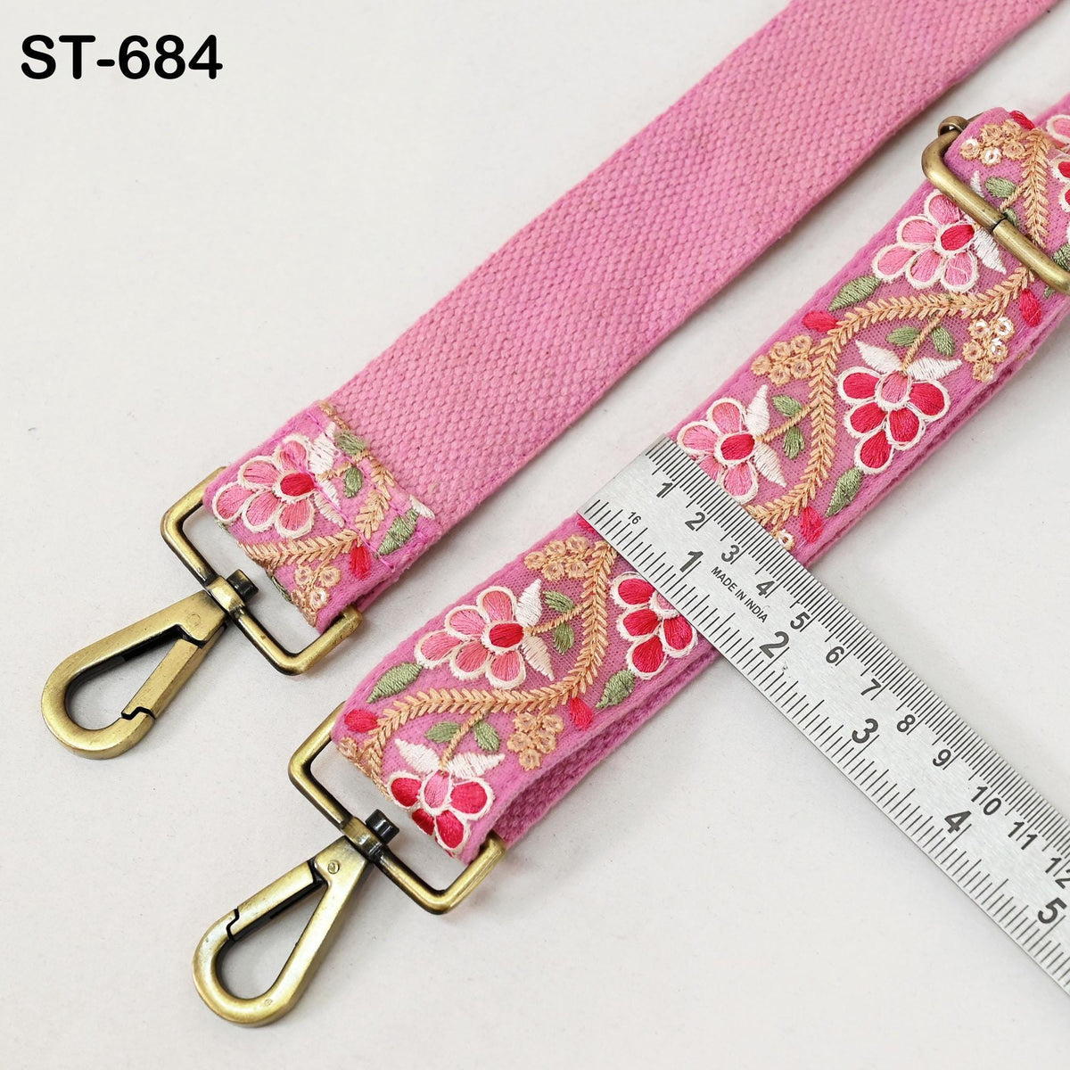 a pink strap with floral embroidery, and a ruler is placed next to it, indicating the strap's length.