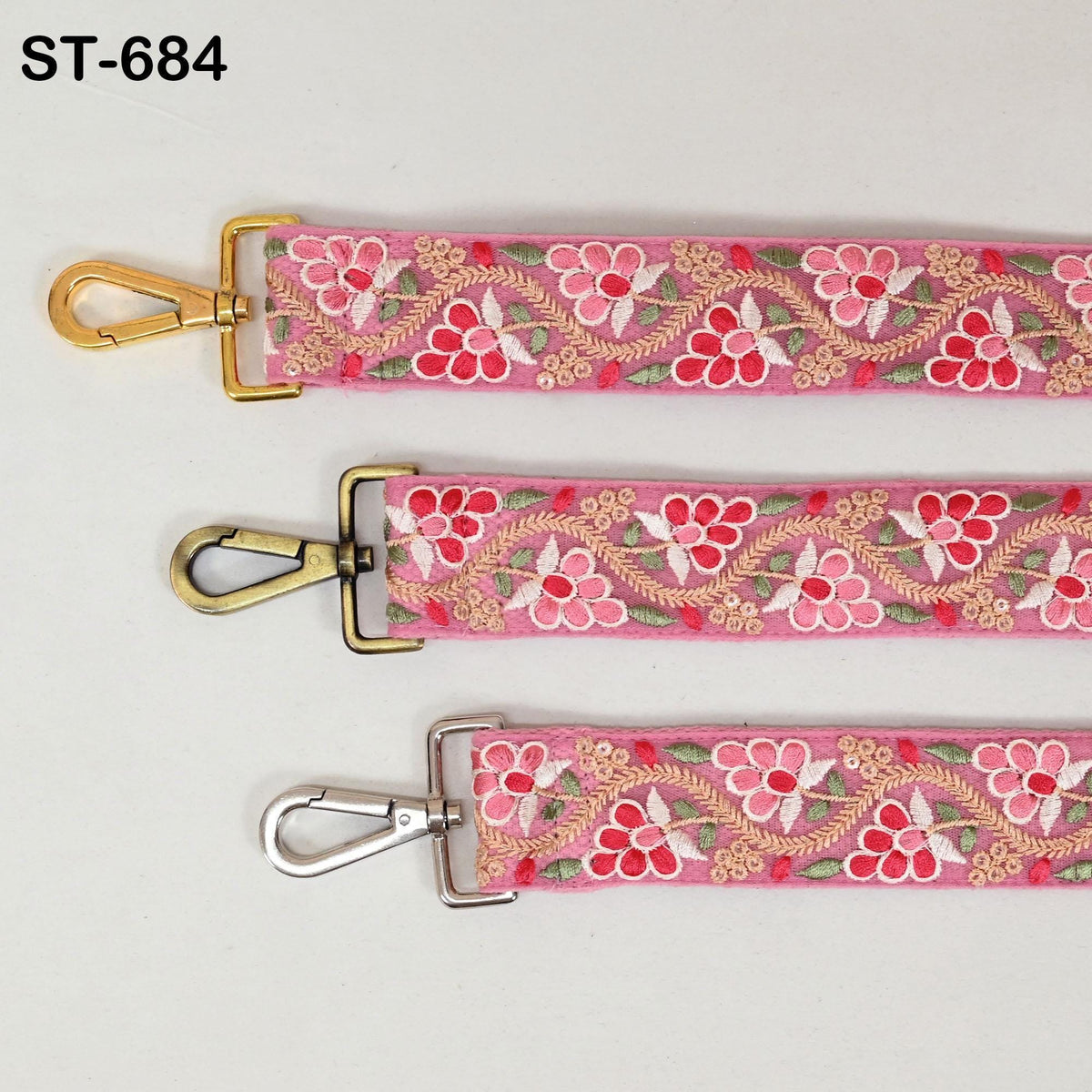 three straps with floral embroidery in pink and red colors. The straps have metal buckles and hooks, and they are arranged in a row.