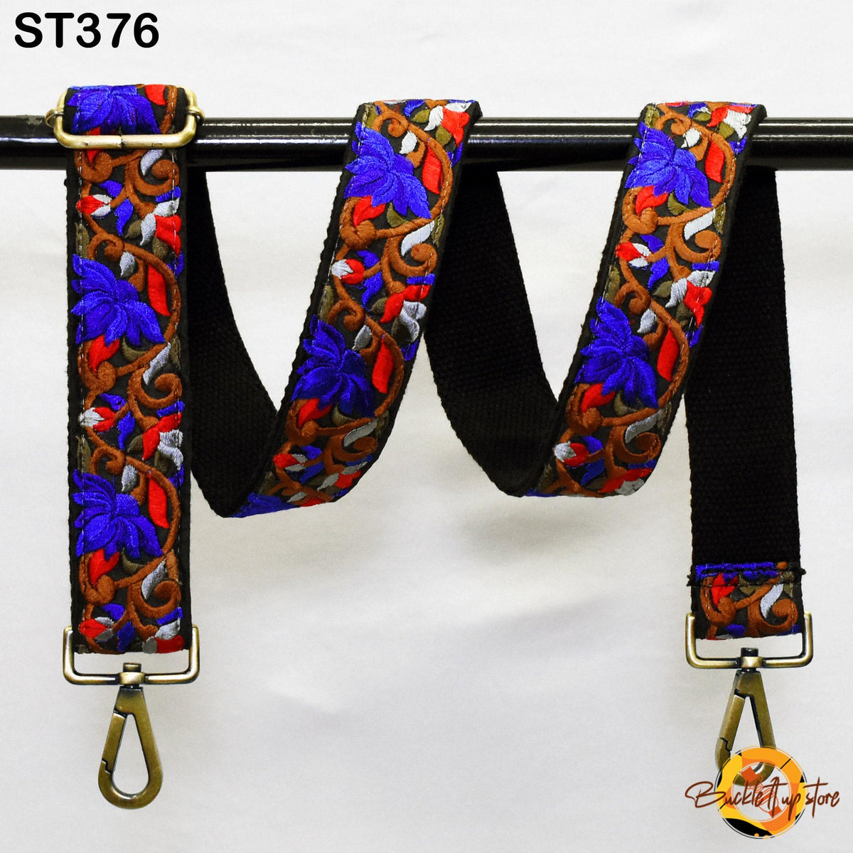 A colorful, patterned strap with a floral design in shades of blue, red, and gold, hanging from a black metal hook.