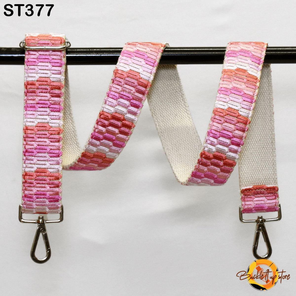 a colorful, patterned strap with a metal clasp and hook attached to a black metal bar.