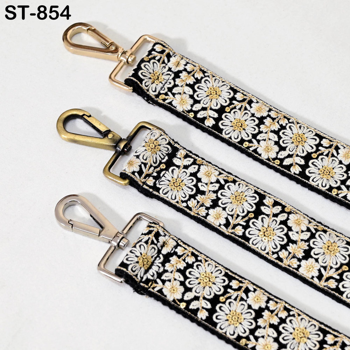 three straps with a floral pattern, each with a metal clasp and hook. The straps appear to be made of fabric and are arranged in a row.