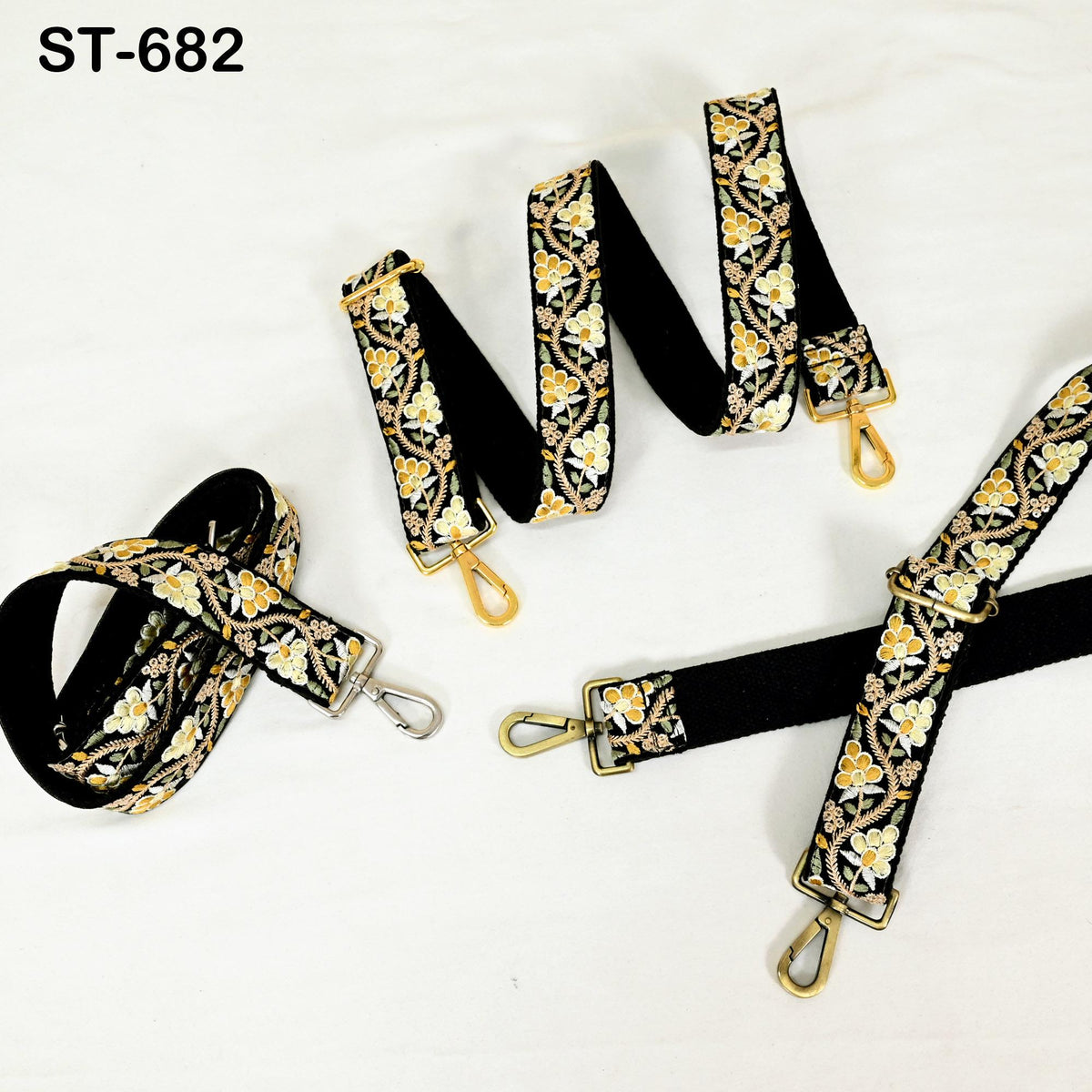 a collection of black and gold floral straps with gold buckles, arranged on a white background.