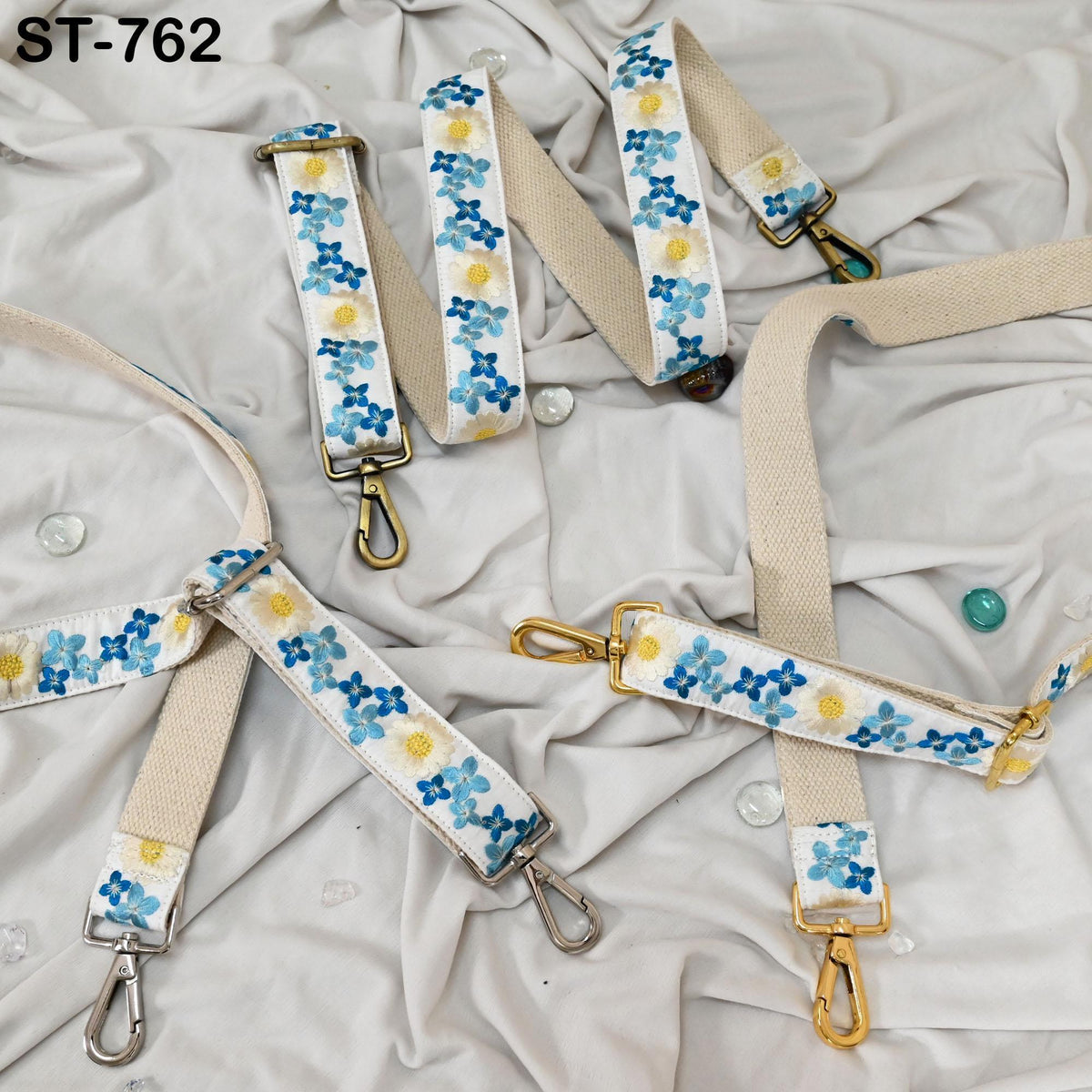 a collection of beige straps with blue floral patterns, arranged on a white fabric surface.