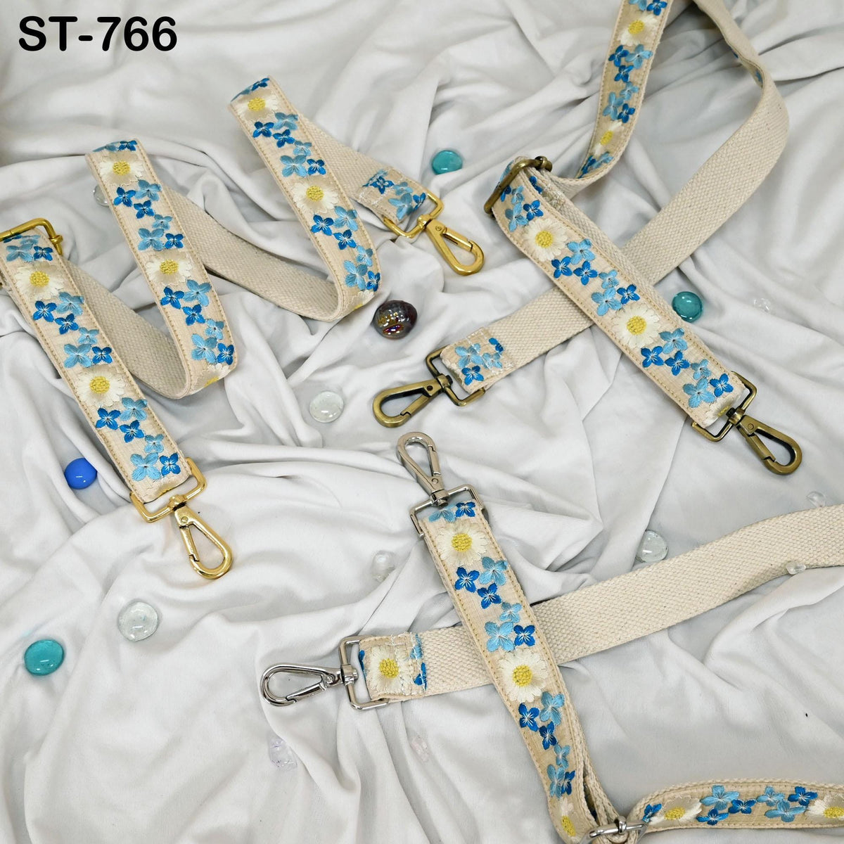 a collection of beige straps with blue floral patterns, scattered on a white cloth.