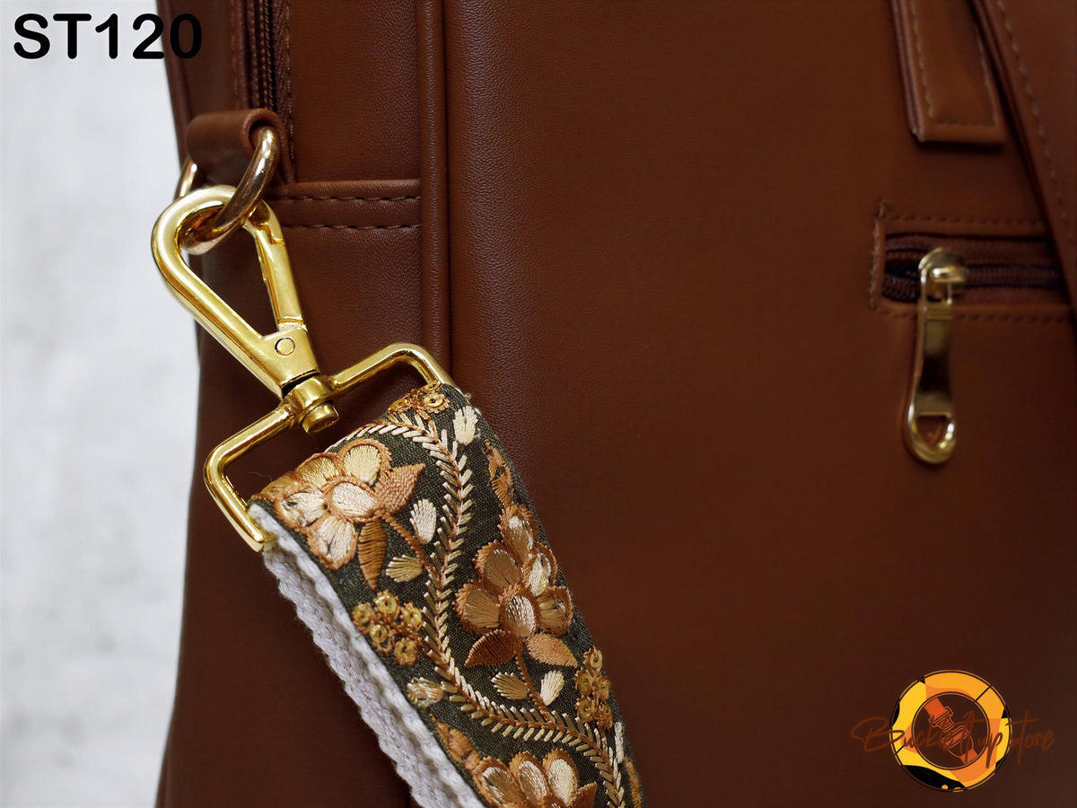 a close-up view of a brown leather handbag with a gold zipper pull and a floral patterned strap.
