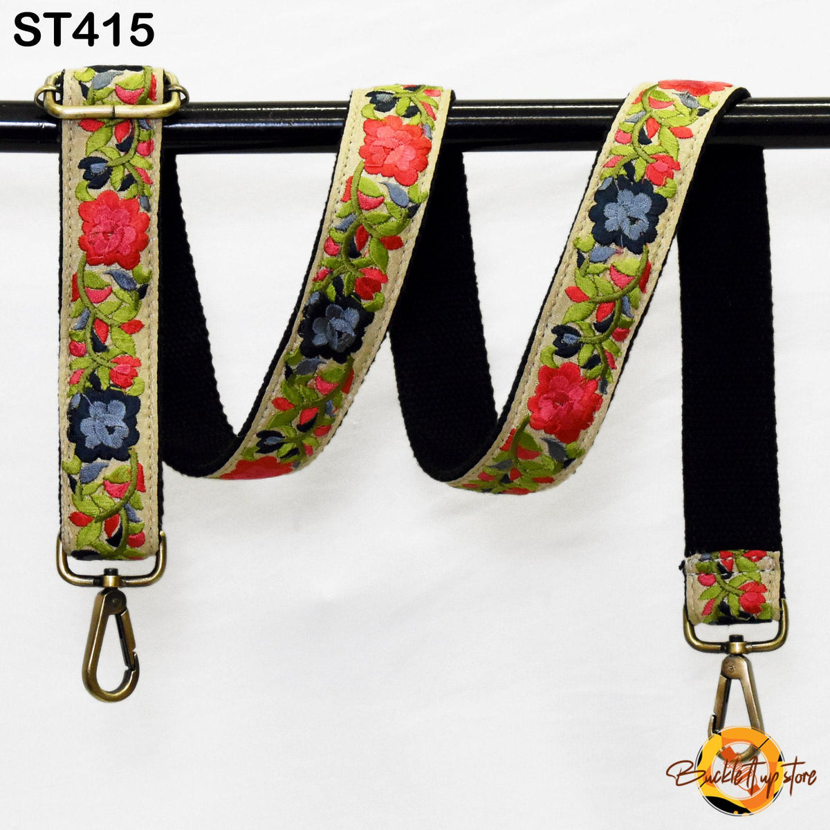 A floral-patterned black strap with red flowers, hanging from a black metal hook.