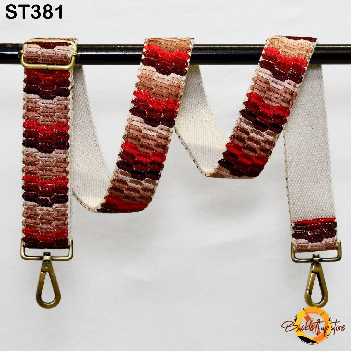 A colorful, patterned strap with a gold-colored buckle attached to a black metal bar.