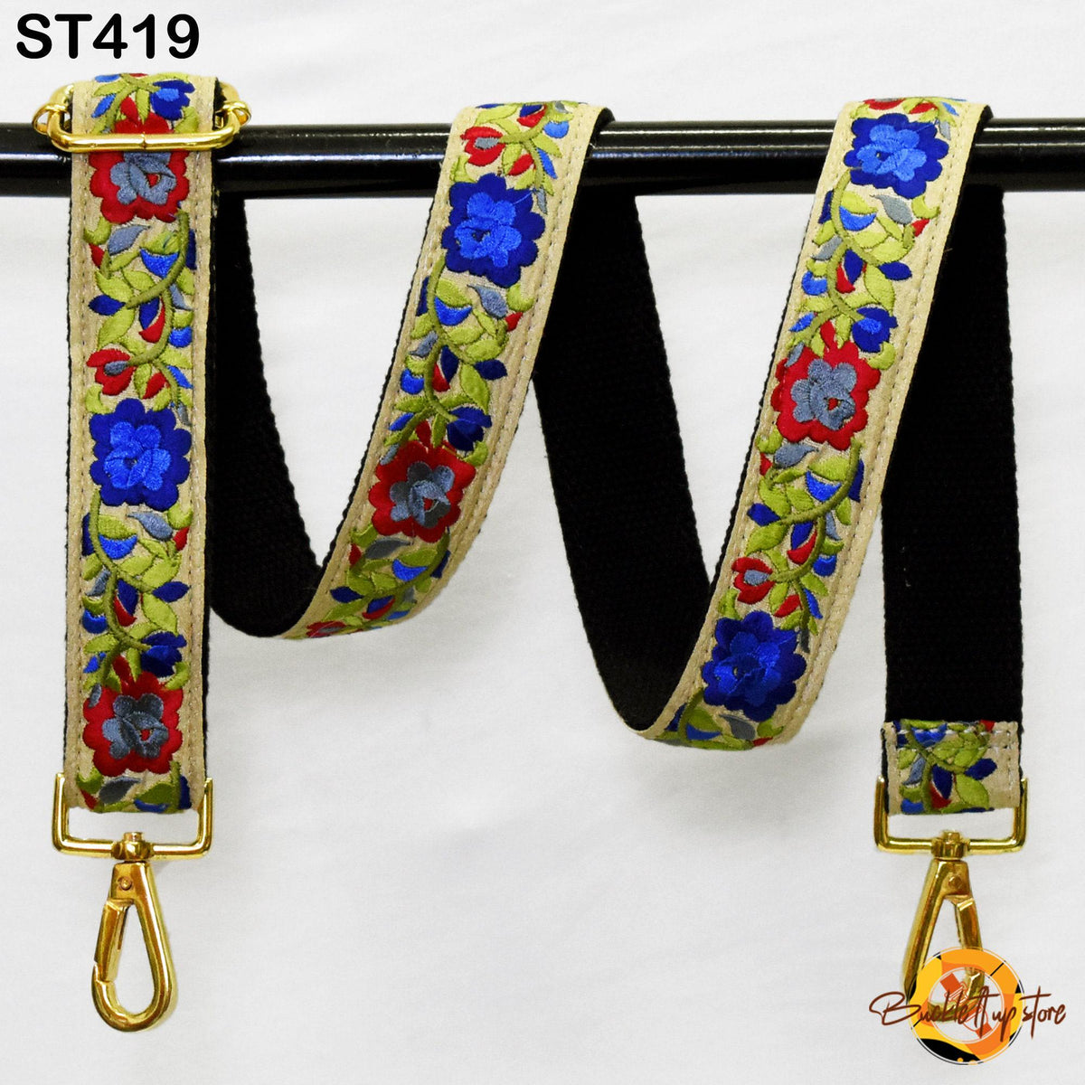 A colorful floral-patterned strap with a gold buckle, hanging on a black rod.