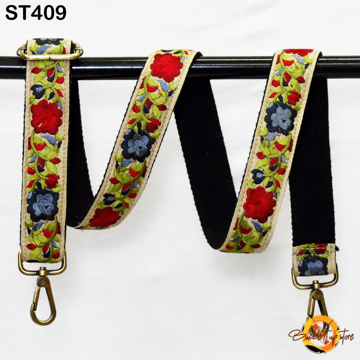 A colorful floral-patterned strap with a black metal buckle, hanging on a black rod.