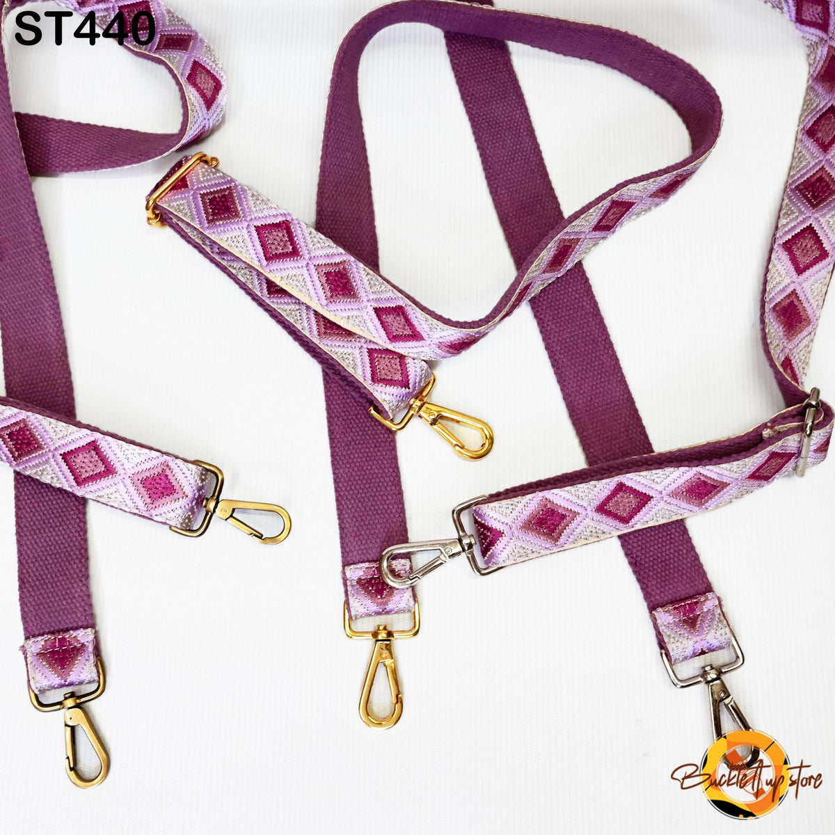 a collection of purple and white patterned straps with gold hardware, including buckles and clips, arranged on a white background.