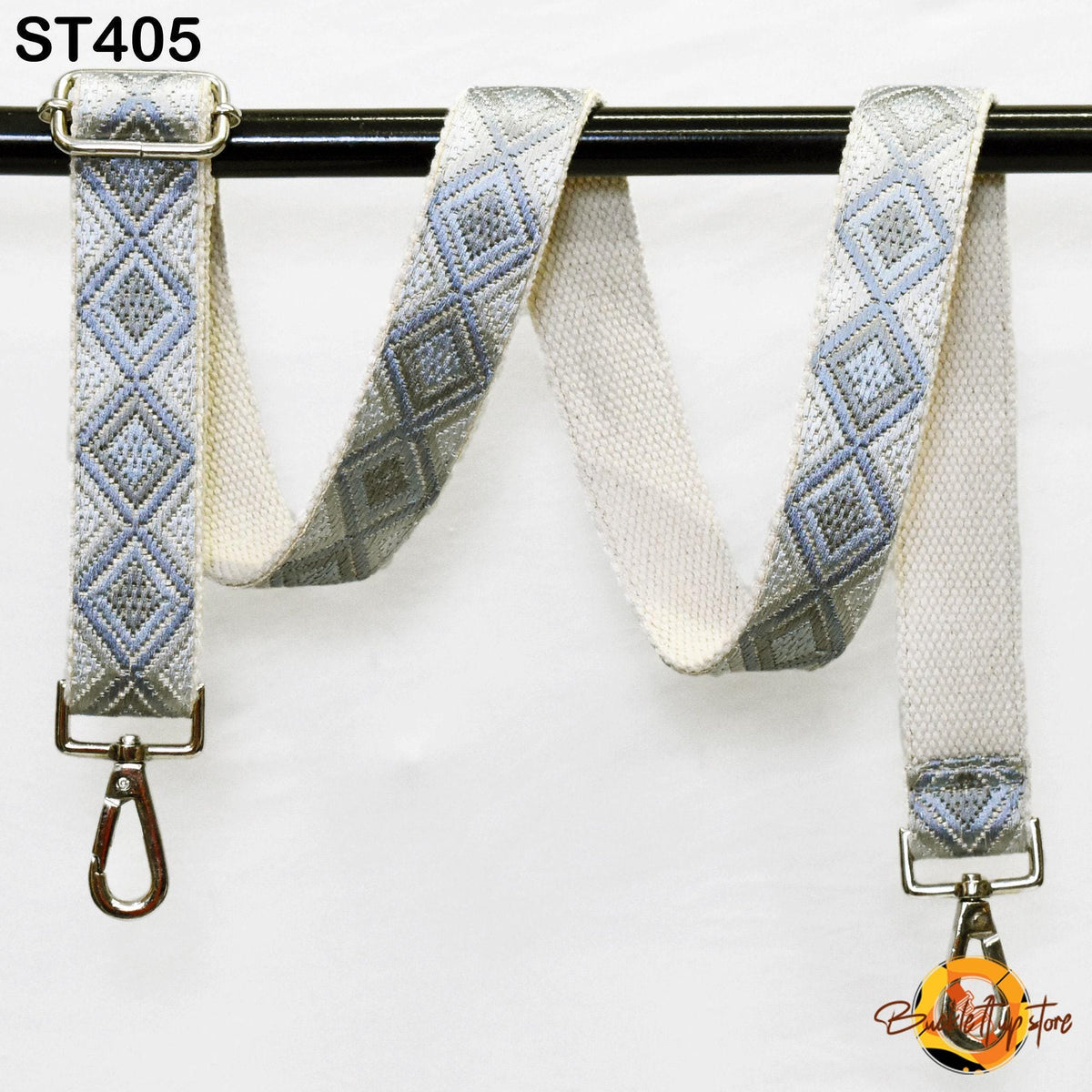 a gray and white patterned strap with a metal hook attached to it, hanging on a black bar.