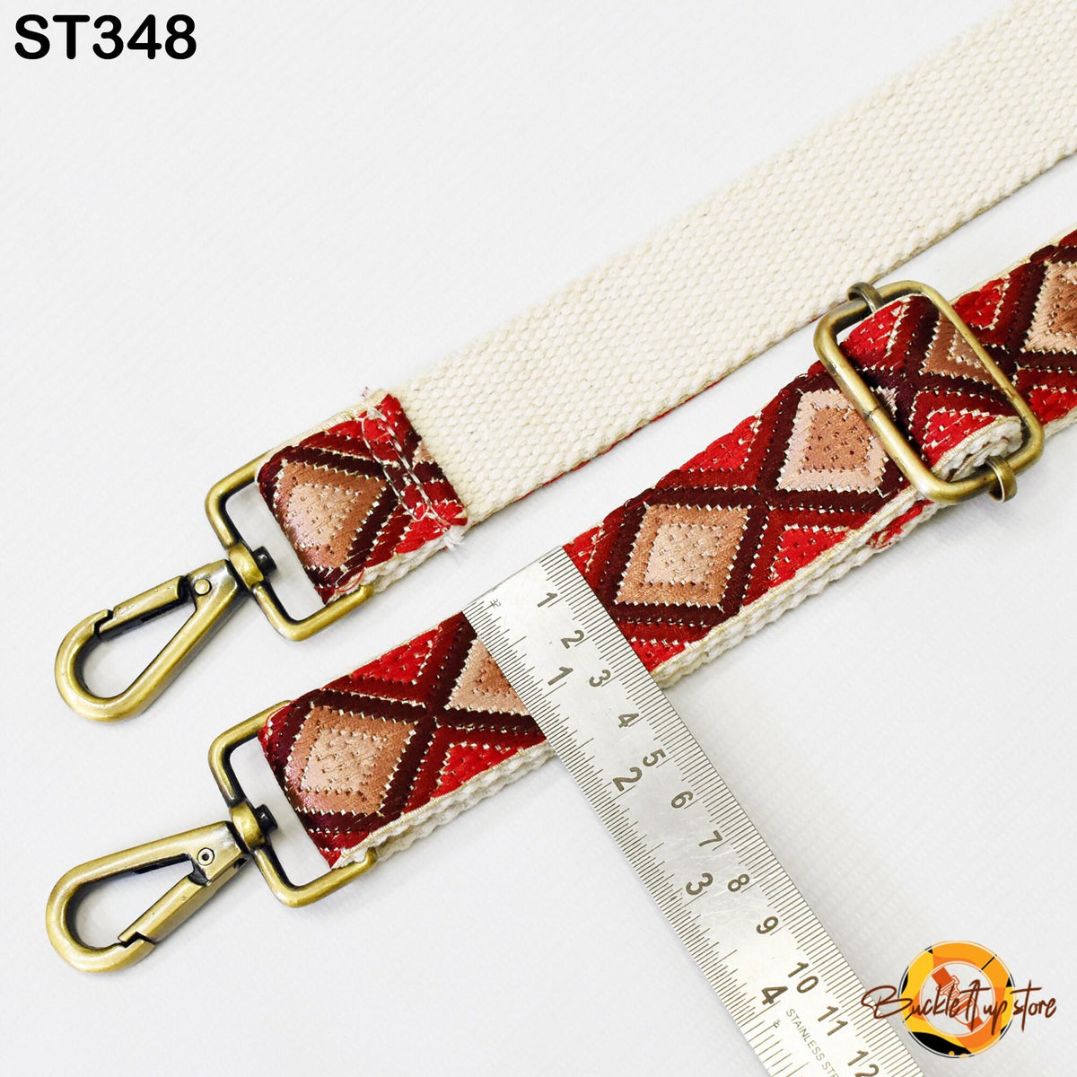 a strap with a red and gold patterned design, and a ruler is placed next to it, indicating the strap's length.