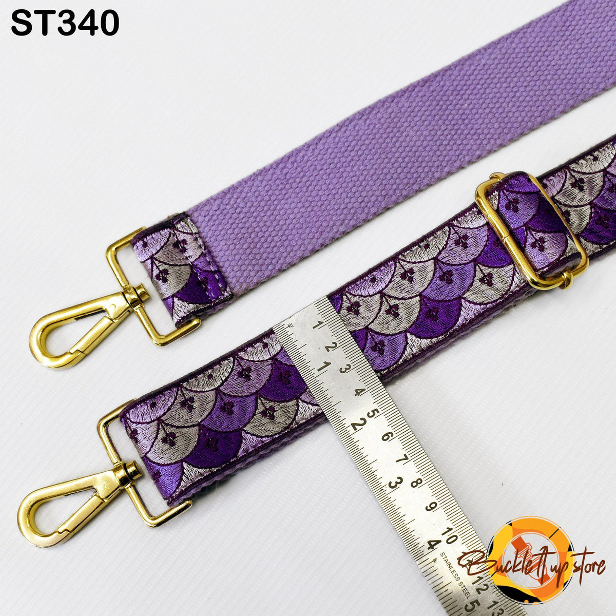 a purple strap with a metallic pattern, and a ruler is placed next to it, indicating the strap's length.