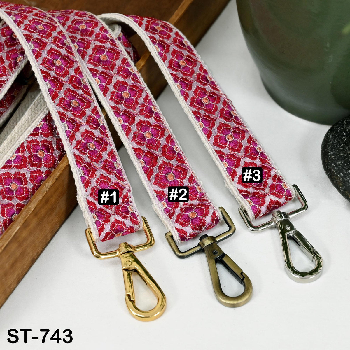 Three colorful straps with metal clasps and tags, each with a different number printed on it.