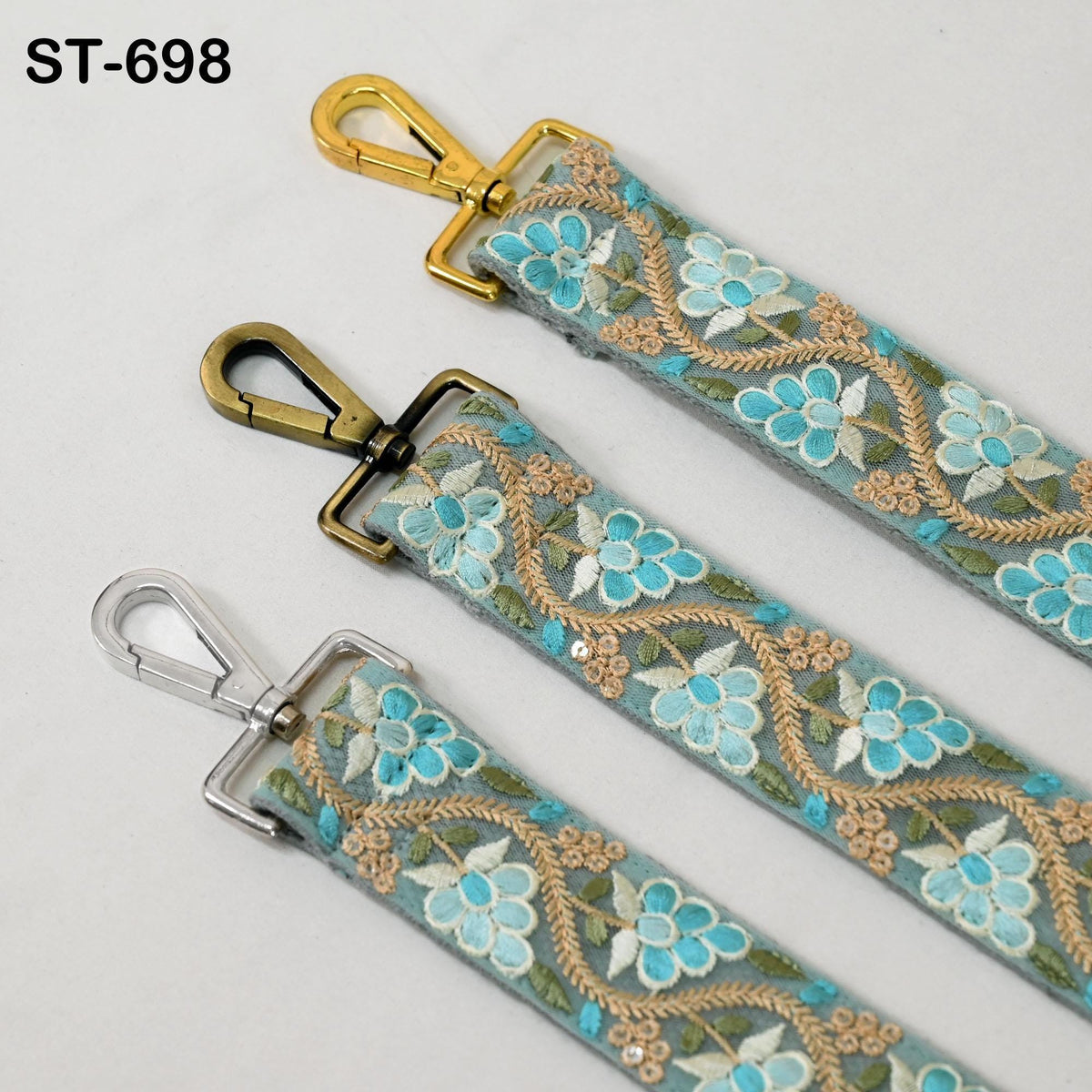 three straps with floral embroidery in shades of blue and gold. The straps have metal clasps and appear to be made of a material that resembles leather.